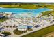 Aerial view of a white sand beach, thatched umbrellas, and beach chairs beside a lagoon at 11728 June Briar Loop, San Antonio, FL 33576