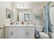 Bright bathroom features double sinks with white cabinets and quartz countertop and tub with shower at 11728 June Briar Loop, San Antonio, FL 33576