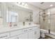 Modern bathroom featuring double sinks with white cabinets and quartz countertop and glass enclosed shower at 11728 June Briar Loop, San Antonio, FL 33576