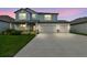 Charming two-story home featuring a three-car garage, covered porch, and beautifully landscaped front yard at dusk at 11728 June Briar Loop, San Antonio, FL 33576