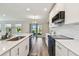 Open-concept kitchen with white cabinetry, stainless steel appliances, and views to the living room and backyard at 11728 June Briar Loop, San Antonio, FL 33576