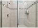 Close up of modern bathroom shower stall with glass doors, neutral tile, and mosaic border at 11728 June Briar Loop, San Antonio, FL 33576