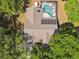 Aerial view of a home with a screened in pool, spa, solar panels, and neutral colored roof at 17904 Singing Wood Pl, Lutz, FL 33548