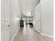 Bright hallway with wood-look tile floor leading to a naturally-lit living room with backyard views at 17904 Singing Wood Pl, Lutz, FL 33548