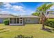 The backyard features a screened-in patio, lush green grass, and mature trees at 14820 Potterton Cir, Hudson, FL 34667