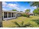 Spacious backyard features a screened-in lanai, lush green grass, and mature landscaping at 14820 Potterton Cir, Hudson, FL 34667