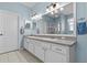 Bright bathroom features a large mirror, double sinks with white cabinets, and blue walls at 14820 Potterton Cir, Hudson, FL 34667