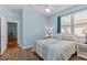 Guest bedroom with blue accent wall, wood floors, ceiling fan and a window with blinds at 14820 Potterton Cir, Hudson, FL 34667