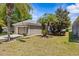 Charming single-story home features a lush lawn, beautiful landscaping, a tidy two-car garage, and mature palm trees at 14820 Potterton Cir, Hudson, FL 34667