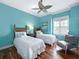 Inviting bedroom with two twin beds, a ceiling fan, wood floors, and a cozy chair by the window at 7020 Hawks Harbor Cir, Bradenton, FL 34207