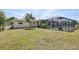 Spacious backyard with lush grass, mature landscaping, and a screened-in pool, perfect for outdoor enjoyment and relaxation at 3067 Iverson St, Port Charlotte, FL 33952