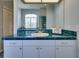 Well-lit bathroom with a vanity featuring blue tiled counter tops, white cabinets, and gold hardware at 802 Eagle Ln, Apollo Beach, FL 33572
