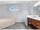 Relaxing bathroom with soaking tub, dark tile floors, and wooden vanity at 11344 Gallinule Ave, Weeki Wachee, FL 34613
