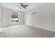 Spacious bedroom with plush carpeting, ceiling fan, and large window at 11344 Gallinule Ave, Weeki Wachee, FL 34613