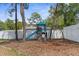 Backyard playset featuring a slide and swing, nestled beneath mature trees and a white vinyl fence at 11344 Gallinule Ave, Weeki Wachee, FL 34613