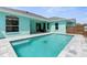 Inviting backyard pool featuring a modern tile surround and a charming aqua-colored home exterior at 11344 Gallinule Ave, Weeki Wachee, FL 34613