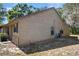 A side exterior shot of a tan house with black shutters and an air conditioning unit at 6175 Beechwood Dr, Dade City, FL 33523