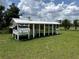 Exterior view of a chicken coop with white siding and a screened run on a grassy lot at 17677 Nectar Flume Dr, Land O Lakes, FL 34637