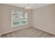 A minimalist, vacant bedroom is lit by a ceiling fan and a large window with outside views at 4804 Myrtle Oak Dr # 11, New Port Richey, FL 34653