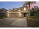Beautiful two-story home with a two-car garage, enhanced by landscape lighting and a palm tree at 12534 Chenwood Ave, Hudson, FL 34669