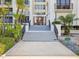 Entrance to white condo building featuring stairs, railing, and lush landscaping at 1400 Gulf Blvd # 701, Clearwater Beach, FL 33767