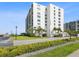 Exterior of white condo building with landscaped green space and parking at 1400 Gulf Blvd # 701, Clearwater Beach, FL 33767