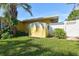 Exterior backyard featuring lawn and mature tree, with a shed and closed white gate at 401 Sunset Dr, Venice, FL 34285