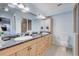 Light and bright bathroom with double sink, granite counters, and blue glass tile backsplash at 401 Sunset Dr, Venice, FL 34285