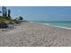 Beach view featuring calming ocean waves, luscious beach vegetation, and a fishing pier in the distance at 401 Sunset Dr, Venice, FL 34285