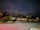 Nighttime view of yellow home with illuminated landscaping and a starlit sky with the moon at 401 Sunset Dr, Venice, FL 34285