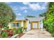 Yellow home with blue shutters, white pergola over the driveway and lush tropical landscaping at 401 Sunset Dr, Venice, FL 34285