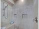 Walk-in shower featuring neutral toned tiles, built-in shelving, and seat at 401 Sunset Dr, Venice, FL 34285