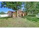 Side view of a two-story peach home with brick paver driveway and large trees at 16601 W Course Dr, Tampa, FL 33624