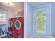 Convenient laundry room featuring red washer and dryer, storage shelves, and access to the outside at 16601 W Course Dr, Tampa, FL 33624