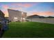 Spacious backyard with a well-maintained lawn, patio seating and a privacy fence on a cloudy sunset at 3270 Rock Sound St, Bradenton, FL 34208