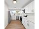 Modern kitchen with white cabinets, stainless steel appliances, wood flooring, and natural light from a window at 5136 Cedar Hammock Dr, Sarasota, FL 34232