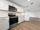 Well-equipped kitchen featuring white cabinets, stainless steel appliances, and an open view to the living area at 5136 Cedar Hammock Dr, Sarasota, FL 34232