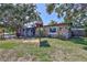Exterior view of a single-story stone-clad home with mature trees and pergola at 6443 34Th N Ave, St Petersburg, FL 33710