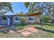 Exterior view of a single-story stone-clad home with pergola and mature trees at 6443 34Th N Ave, St Petersburg, FL 33710