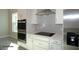 Modern kitchen featuring stainless steel appliances, white cabinetry, and a sleek cooktop at 9544 Brave Buck Ave, Land O Lakes, FL 34638