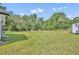 Expansive backyard featuring lush green grass, mature trees, and a storage shed with a carport at 13091 Old Crystal River Rd, Brooksville, FL 34601