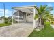 Charming home with a covered carport, screened-in porch, and a neatly landscaped yard with a palm tree at 9790 66Th N St # 89, Pinellas Park, FL 33782
