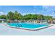 Large community pool surrounded by mature trees, lounge chairs, and a gated fence at 9790 66Th N St # 89, Pinellas Park, FL 33782