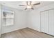 Bright bedroom with light wood floors, a ceiling fan, a window with blinds, and a double-door closet at 2139 Stellar Brilliance Way, Lutz, FL 33558