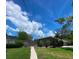 A fenced-in backyard with a path leading to a house, surrounded by trees and greenery under a bright sky at 4571 Clearwater Harbor S Dr, Largo, FL 33770