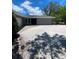 Charming home with a gravel driveway leading to the garage, surrounded by lush landscaping at 4571 Clearwater Harbor S Dr, Largo, FL 33770