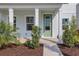 Inviting front porch with white columns and a modern green front door, surrounded by landscaping at 130 Bragg Ln, Lakewood Ranch, FL 34240