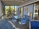 A covered patio features a beautiful glass table with blue metal chairs and a peaceful place to relax at 1612 Pocatello St, Sarasota, FL 34231