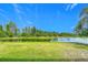 Expansive backyard with lush green grass and a serene lake view, framed by beautiful trees at 18441 New London Ave, Land O Lakes, FL 34638