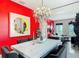 Elegant dining area with a striking red accent wall, chandelier, and a view into the adjacent living space at 18441 New London Ave, Land O Lakes, FL 34638